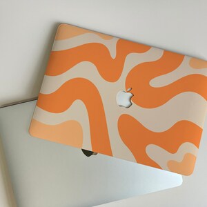 May include: A laptop computer with a beige and orange abstract swirl pattern on the lid. The Apple logo is visible on the lid.