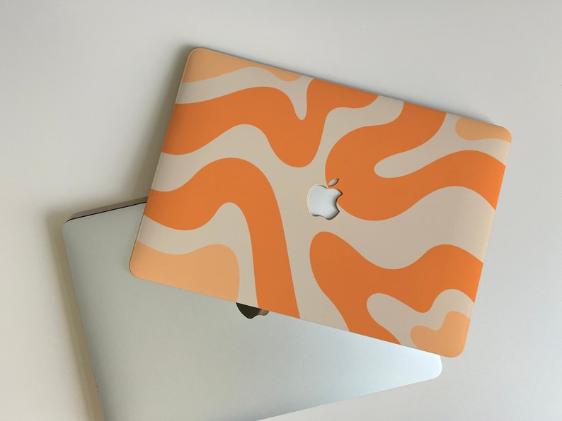 May include: A laptop computer with a beige and orange abstract swirl pattern on the lid. The Apple logo is visible on the lid.