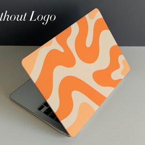 May include: A laptop computer with a light orange and cream abstract swirl pattern on the lid. The laptop is open and the keyboard is visible.