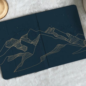 May include: A dark blue phone case with a gold outline of mountains against a starry night sky.