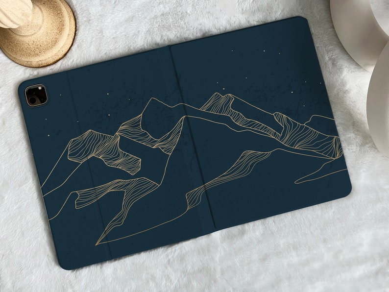 May include: A dark blue phone case with a gold outline of mountains against a starry night sky.