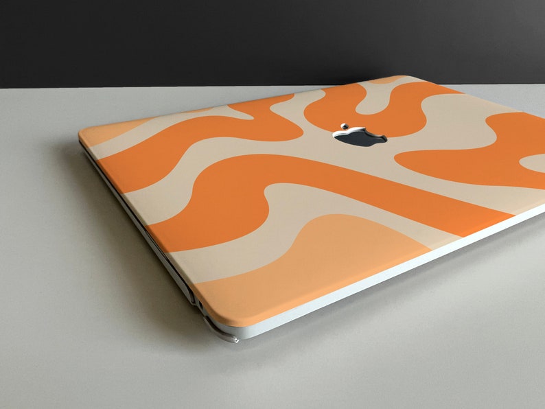 May include: A white laptop with an orange and cream abstract swirl pattern on the lid. The Apple logo is visible on the lid.