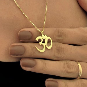 Op de afbeelding: Een gouden ketting met een gouden Om-hanger. De hanger is een gestileerd symbool van het Sanskriet woord Om.