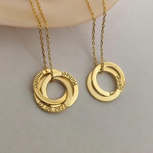 May include: Two gold necklaces with interlocking rings. The rings are engraved with the names "Michael", "Daniel", and "Jennifer" and the date "02.06.2022".