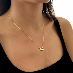 K&ouml;nnte beinhalten: Eine goldene Kettenkette mit einem Anh&auml;nger, auf dem "111" in einer fetten, blockartigen Schrift steht.