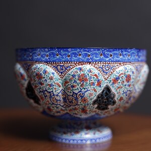 May include: A blue and white ceramic bowl with intricate floral and geometric patterns. The bowl has a wide rim and a pedestal base.