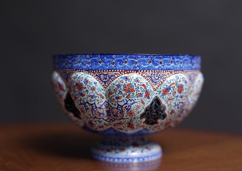 May include: A blue and white ceramic bowl with intricate floral and geometric patterns. The bowl has a wide rim and a pedestal base.