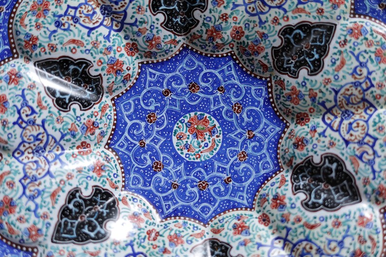 May include: A blue and white ceramic plate with intricate floral and geometric designs. The center of the plate features a circular design with red, green, and blue accents.