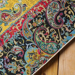May include: A close-up of a colorful fabric with a paisley pattern. The fabric is a mix of red, yellow, blue, green, and black. The fabric is woven with a variety of textures, including smooth, rough, and shiny.