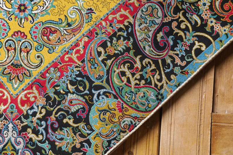 May include: A close-up of a colorful fabric with a paisley pattern. The fabric is a mix of red, yellow, blue, green, and black. The fabric is woven with a variety of textures, including smooth, rough, and shiny.
