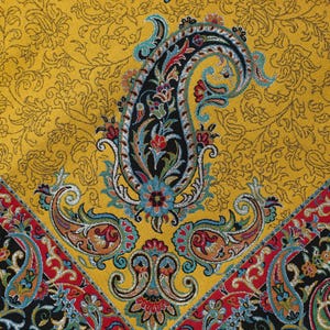 May include: A yellow fabric with a paisley pattern. The paisley pattern is in shades of blue, red, and black. The fabric has a textured surface.
