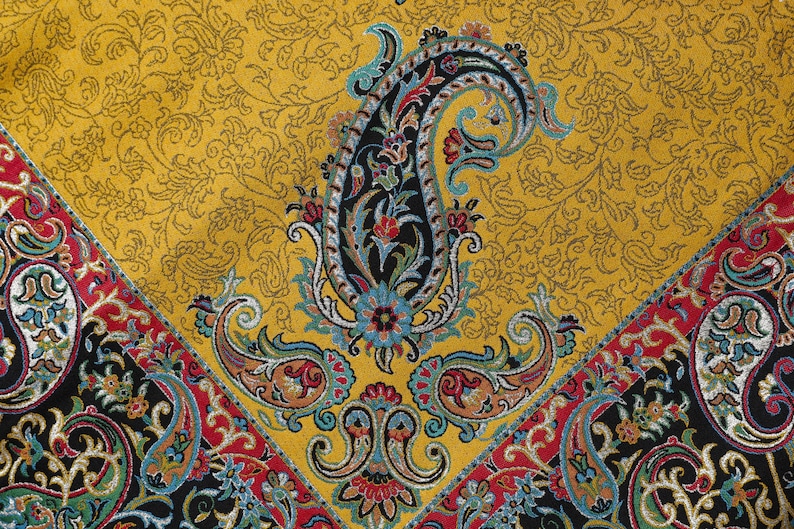 May include: A yellow fabric with a paisley pattern. The paisley pattern is in shades of blue, red, and black. The fabric has a textured surface.