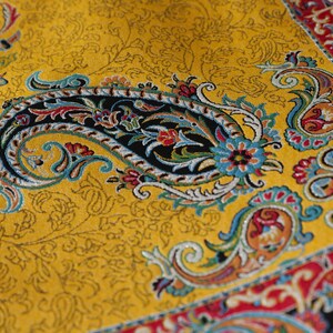 May include: A yellow fabric with a paisley pattern in shades of blue, red, green, and black. The fabric has a traditional Persian design.