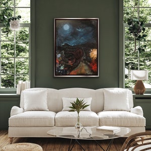 May include: A framed abstract painting depicting a dark, nighttime landscape with a bright moon and stars. The painting is set against a dark green wall in a living room setting with a white sofa and a glass coffee table.