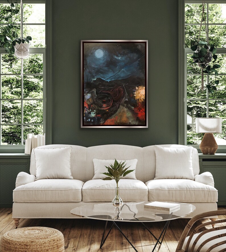 May include: A framed abstract painting depicting a dark, nighttime landscape with a bright moon and stars. The painting is set against a dark green wall in a living room setting with a white sofa and a glass coffee table.