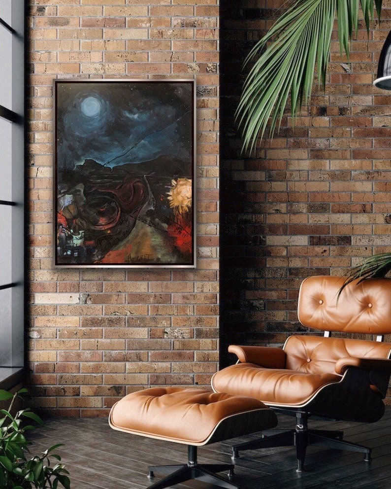 May include: A painting of a dark, moonlit landscape with a red road leading to a bright yellow sun in the distance. The painting is framed in a silver frame and is hanging on a brick wall.