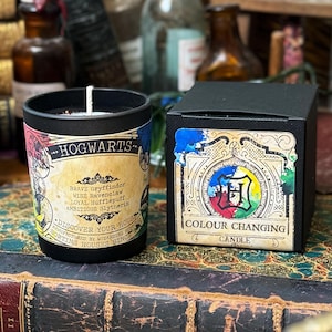 May include: A black Hogwarts candle with a white wick and a matching box. The candle label reads "Hogwarts" and lists the four houses. The box says "Colour Changing Candle".