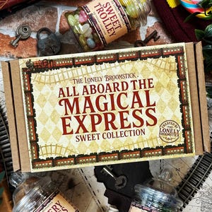 May include: A themed sweet collection box with the text "All Aboard The Magical Express Sweet Collection". The box is brown with a diamond pattern and train illustrations. Jars of sweets, keys, and a toy train are also visible.