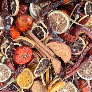 Może przedstawiać: Mieszanka suszonych owoców i przypraw, w tym czerwonych papryczek chili, plastrów pomarańczy i cytryny, jabłek i cynamonowych patyczków.