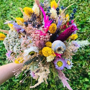 Pu&ograve; includere: Un bouquet di fiori secchi con una variet&agrave; di colori, tra cui rosa, giallo, viola e bianco. Il bouquet comprende fiori secchi, erbe e baccelli di semi.