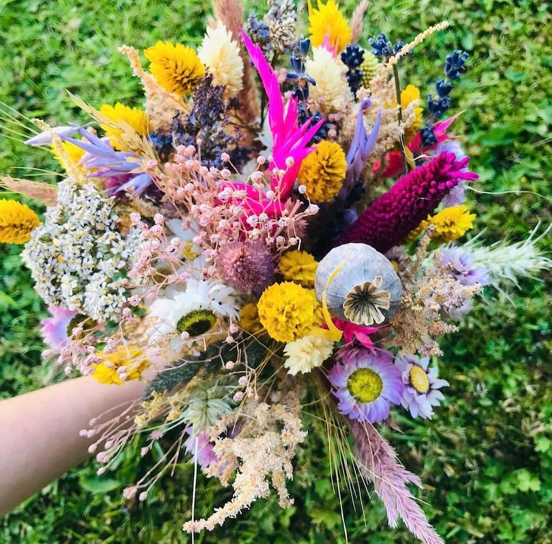 Pu&ograve; includere: Un bouquet di fiori secchi con una variet&agrave; di colori, tra cui rosa, giallo, viola e bianco. Il bouquet comprende fiori secchi, erbe e baccelli di semi.