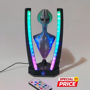 May include: An alien-themed lamp with a gray alien figure and vertical light bars with color-changing LEDs. Includes a remote control. The base has a logo and the words "SPECIAL PRICE".