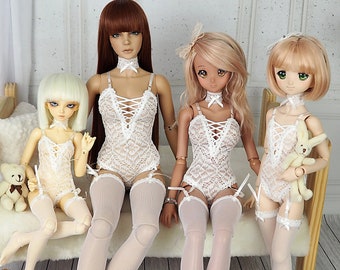 Può includere: Quattro bambole vestite con lingerie di pizzo bianco con calze bianche abbinate. Le bambole sono sedute su una panca di legno con un cuscino bianco e soffice. Due delle bambole tengono orsacchiotti.