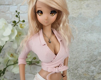 May include: A doll with long blonde hair wearing a pink collared top with a bow and white pants with a floral print.