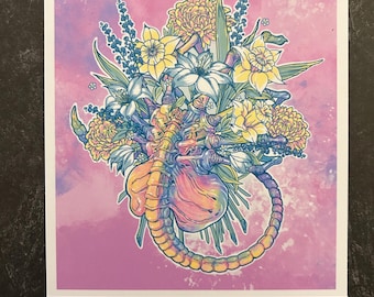 May include: A colorful illustration of a floral arrangement with a pink, yellow, and blue alien creature in the center. The creature is surrounded by yellow daffodils, white flowers, and green leaves. The background is a soft pink with a watercolor effect.