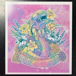May include: A colorful illustration of an alien creature surrounded by flowers. The alien is depicted in shades of green, purple, and yellow, with a detailed, open mouth. The flowers include yellow daffodils, white lilies, and other blooms, set against a pink background.