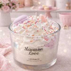 Puede incluir: Vela de cristal transparente con la inscripción "Macaron Love", cubierta con crema batida, chispas de colores y macarons. Elaborada con cera de soja natural y 100% vegana.