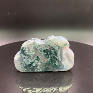 May include: A green and white agate stone carved into the shape of a cloud. The stone has a natural, organic look with swirls of green and white.