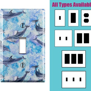 May include: Light blue and white watercolor light switch cover with a pattern of dolphins swimming in the ocean.  The text "All Types Available" is displayed above a row of five different light switch cover options.