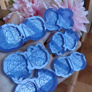 May include: A set of eight blue silicone molds with a cloud and swirl design. The molds are held in a hand and have the text "@moonlightmolds" on them.