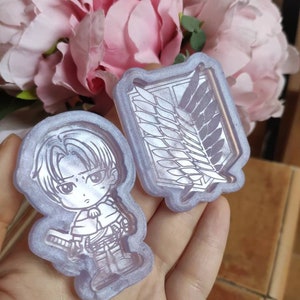 May include: Two clear silicone molds, one with a cartoon character and the other with the Wings of Freedom symbol from the anime Attack on Titan.