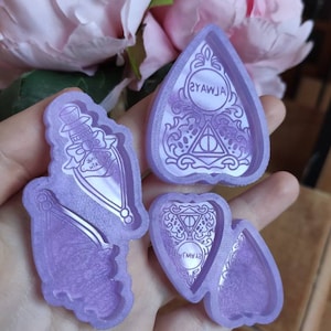 Puede incluir: Cuatro moldes de silicona púrpura para fundición de resina. Los moldes tienen forma de botella, mariposa y dos corazones invertidos. Los corazones tienen un diseño de triángulo y círculo con el texto "Always" y "Always" escrito en su interior.