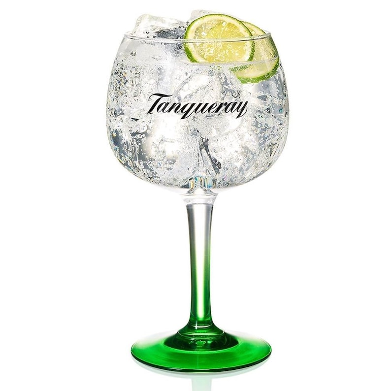 Puede incluir: Un vaso alto y transparente con tallo y base verdes, lleno de hielo y un l&iacute;quido transparente. El vaso tiene la palabra "Tanqueray" impresa en el lateral. Una rodaja de lima flota sobre el hielo.