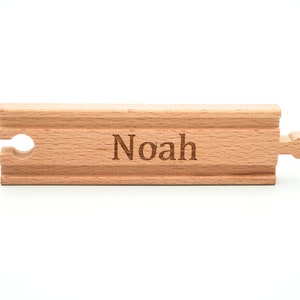 May include: A wooden train track piece with the name "Noah" engraved on it.