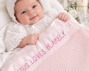 Può includere: Una morbida coperta per neonati rosa con bordo in raso caratterizzata dal testo ricamato JESUS LOVES BLAKELY in filo rosa. La coperta presenta un motivo a nido d'ape testurizzato ed è abbinata a una cuffietta bianca con pizzo e vestiti bianchi.