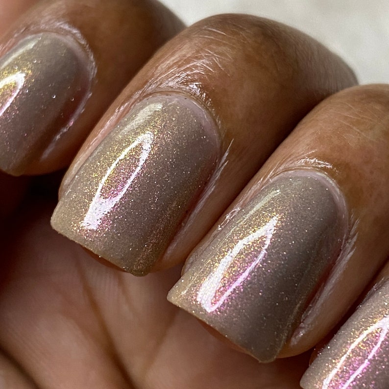 Puede incluir: Primer plano de cuatro u&ntilde;as pintadas con un esmalte de u&ntilde;as marr&oacute;n claro con un sutil brillo iridiscente.