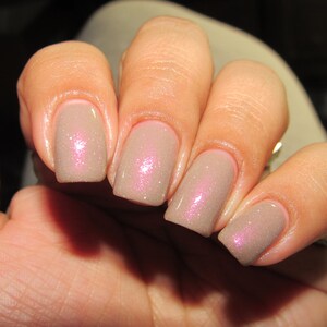Puede incluir: Primer plano de cinco u&ntilde;as pintadas con un esmalte de u&ntilde;as marr&oacute;n claro con un sutil brillo rosado.