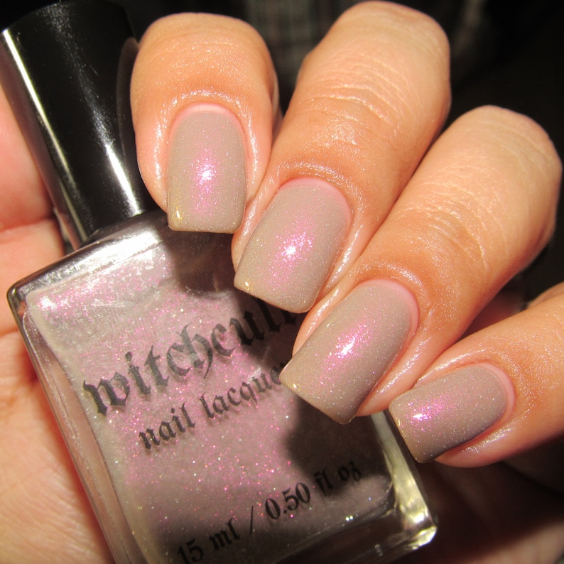 Puede incluir: Una botella de esmalte de u&ntilde;as Witchcraft de color rosa claro con un acabado brillante. La botella est&aacute; etiquetada con el nombre de la marca y el texto "nail lacquer". La botella es de 15 ml / 0.50 fl oz.