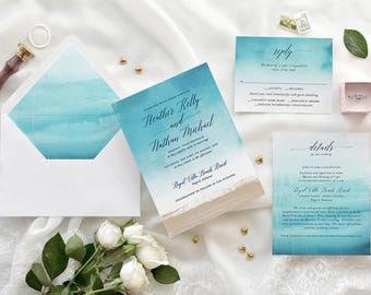May include: Wedding invitation suite with a watercolor design featuring shades of blue and white. The invitation includes the names "Heather Kelly and Nathan Michael", the date "August 12th", and the location "Royal Villa Beach Resort".