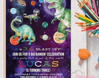 May include: A colorful invitation with a space theme, featuring dinosaurs in astronaut helmets against a purple galaxy backdrop. Text reads "Lucas is turning three!" with event details. Includes a pencil holder and a monkey-shaped stamp.