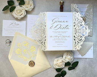 May include: White wedding invitation with a laser cut design. The invitation features the names Gianna & Destin and the date September 24th. The invitation is decorated with white roses and a wax seal.