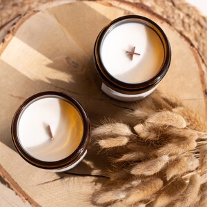 Vista superior de dos velas en frascos ámbar con una superficie perfecta de cera de soja. En el interior de las velas, se aprecian dos tipos de mechas : una clásica y la otra en forma de cruz.