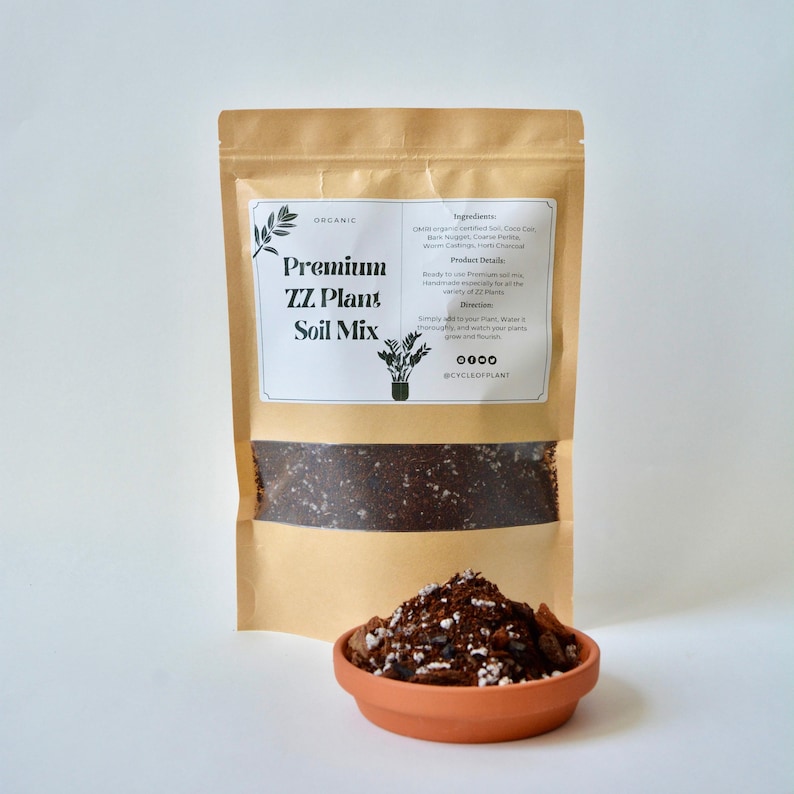 May include: A brown paper bag with a label that reads "Organic Premium ZZ Plant Soil Mix". The bag contains a dark brown soil mix. The label also lists the ingredients and directions for use. The bag is sitting on a white surface.