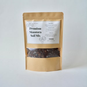 May include: A brown paper bag with a clear window showing a dark brown soil mix. The bag has a white label with the text "ORGANIC Premium Monstera Soil Mix" and a list of ingredients and directions. The label also includes a black and white illustration of a Monstera plant.