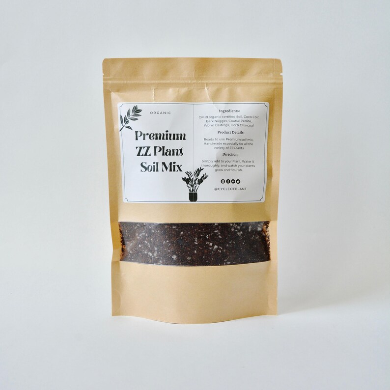 May include: A brown paper bag with a white label that says "Premium ZZ Plant Soil Mix" and lists the ingredients and directions for use. The bag is filled with dark brown soil.
