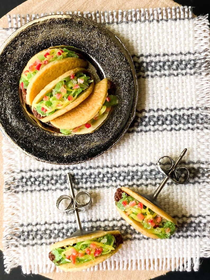 Peut inclure: Une paire de boucles d'oreilles en forme de taco argent&eacute;es avec un design r&eacute;aliste. Les boucles d'oreilles pr&eacute;sentent un petit taco d&eacute;taill&eacute; avec une tortilla jaune, de la laitue verte, une tomate rouge et une garniture brune. Les boucles d'oreilles sont parfaites pour ajouter une touche amusante et d&eacute;cal&eacute;e &agrave; n'importe quelle tenue.